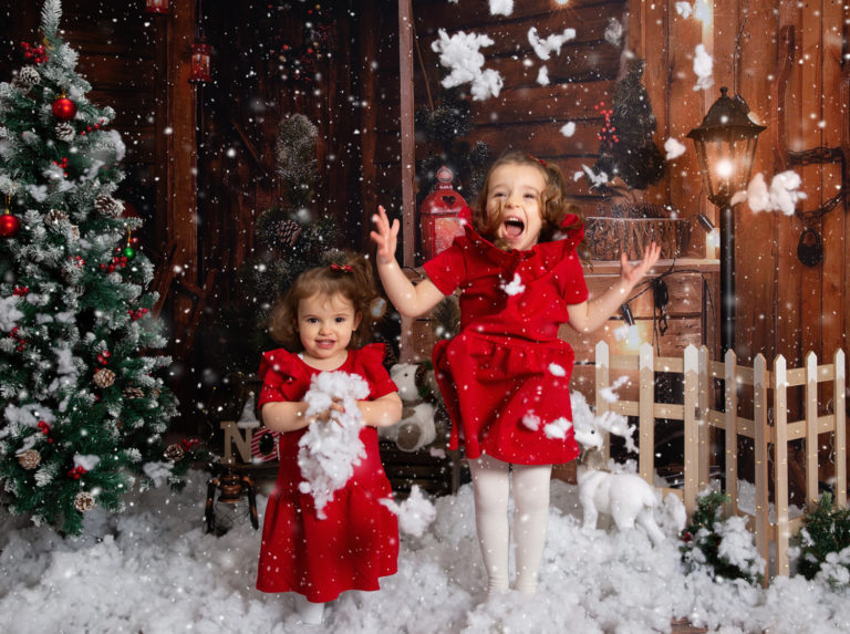 Photographie de deux petites filles habillées en rouge, lors d'un shooting photo de Noël.