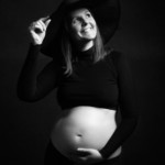 Femme enceinte souriant, posant lors d'une séance photo grossesse, réalisée par Béregère Grassin du studio Bérengère, votre photographe professionnelle dans les Yvelines.