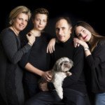 Une famille souriante lors d'une séance photo studio en famille réalisée sur un fond noir.