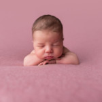 Un nouveau-né serein, posé sur la table des bébés pour sa séance pack-maternité.