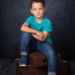 Un petit garçon heureux de poser pour sa séance portrait.