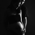 Une photographie d'un couple, en noir et blanc, mettant en avant la grossesse de la jeune femme.